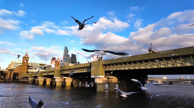 Cannon Street Railway Bridge, The Square Mile, river Thames and a flock of seagulls fluttering in ultra-slow motion in London, England, UK on a sunny afternoon