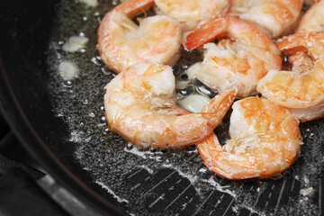 Garlic butter shrimp frying closeup. Seafood cooking in pan. Hot oil and garlic aroma. Fresh prawns on skillet. Tasty dinner preparation. Simple home recipe with seafood and butter.