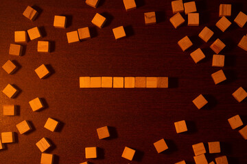 Row of Wooden Cubes on Warm Dark Tabletop With Scattered Wood Blocks, Artistic Arrangement Display.
