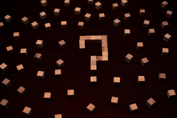 Question Mark Built From Wooden Cubes Among Scattered Blocks on a Dark Wooden Table