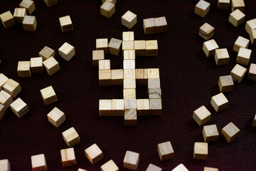 Wooden Block Puzzle Forming a Dollar Sign Amid Scattered Cubes on Dark Surface