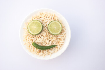 Smiley Puffed Rice Bowl With Lime Eye Slices And Chili Smile In Puffed Rice. Smiley made with puffed rice, lime slice, and green chili in a white bowl.