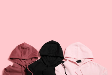 Stylish hoodies on pink background