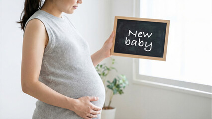 Pregnant woman holding new baby chalkboard in bright room, expectant mother maternity concept with window light and plant, anticipation of childbirth joy and motherhood happiness lifestyle concept