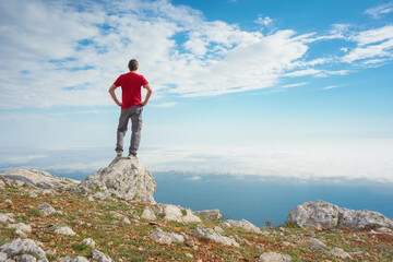Man on sea cliff edge and blue sky at spring day.