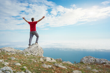 Man on sea cliff edge and blue sky at spring day.
