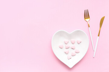Table setting for Valentine's Day with confetti and decorative hearts on pink background