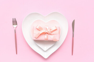 Table setting for Valentine's Day with gift box on pink background