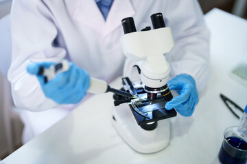 Adult scientist researcher uses microscope pipetting sample in laboratory for medical science biotechnology academic research experiment