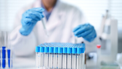 Adult scientist in lab coat performing precise laboratory research handling multiple test tubes for medical analysis and scientific discovery in a modern facility