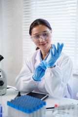 Asian adult female scientist dons blue protective gloves for lab work scientific research experiment safety medical hygiene