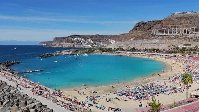 The Turquoise Sanctuary: 4K Aerial of Playa de Amadores Beach and Cliffside 5-Star Resorts, featuring Gloria Palace and RIU Vistamar, Gran Canaria, Spain