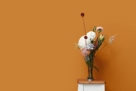 Kenzan with ikebana on table near orange wall