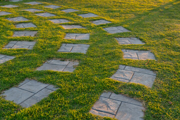The square stepping stones are arranged in the green grass.