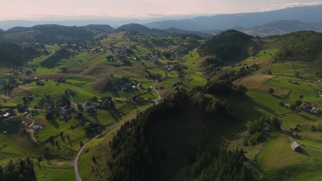 Stunning Aerial Pan over Fundata Village Hills and Long Shadows during Late Afternoon Golden Hour in Transylvania Romania