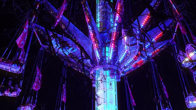 Colorful illuminated swing carousel amusement ride at a Christmas market in Paris at night