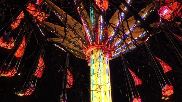 Colorful illuminated swing carousel amusement ride at a Christmas market in Paris at night