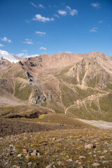 Winding gravel road in the high mountains of Tien Shan with a view of the massive Tuyuksu glacier. Remote alpine landscape in Central Asia
