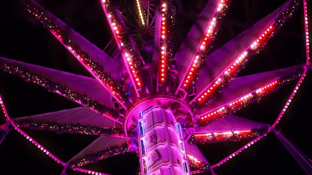 Colorful illuminated swing carousel amusement ride at a Christmas market in Paris at night