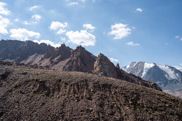Winding gravel road in the high mountains of Tien Shan with a view of the massive Tuyuksu glacier. Remote alpine landscape in Central Asia