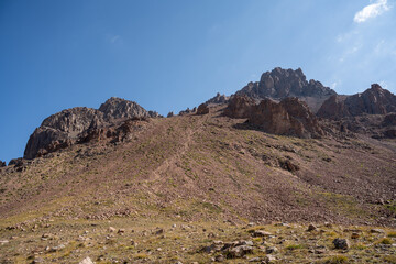 Winding gravel road in the high mountains of Tien Shan with a view of the massive Tuyuksu glacier. Remote alpine landscape in Central Asia