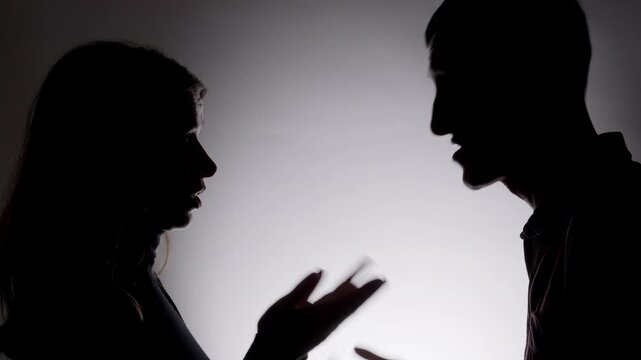 A man and a woman are arguing aggressively, close-up of their silhouettes. Conflict concept. Quarrel between a couple.