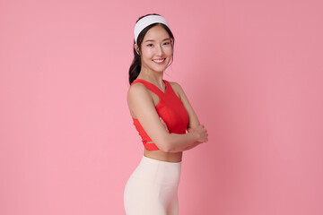 Fitness lifestyle portrait smiling Asian woman in activewear standing confidently healthy body concept workout motivation wellness and self care modern sport fashion studio pink background.