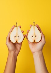 two hands holding halves of a pear against yellow background