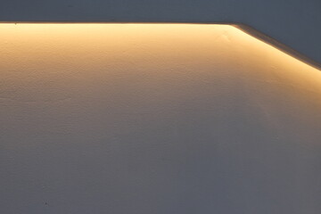 Warm ambient light illuminates a textured wall surface with subtle shadows and highlights