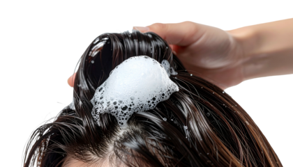 Person's hair being washed with foamy shampoo. Hand massages scalp, revealing wet hair