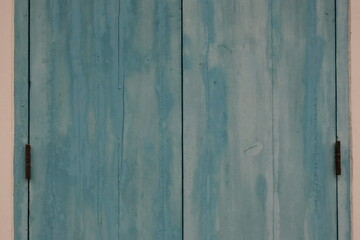 Obraz premium Weathered blue wooden shutters with visible grain and hinges