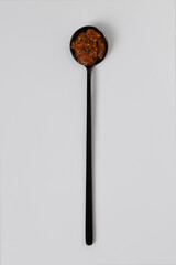 Homemade spicy chili sauce with peppers in black teaspoon