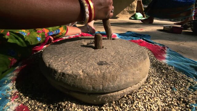 An Indian village woman grinding black gram lentils on a hand-driven stone mill showcases traditional agriculture-based lifestyles, homemade food culture, and timeless rural craftsmanship.