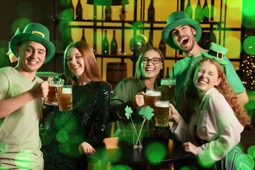 Group of friends with beer celebrating St. Patrick's Day in pub at night