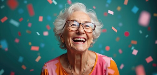 Elderly woman laughs happily with glasses on. Confetti rains down on her teal backdrop. She celebrates a joyous occasion, like a birthday or winning lottery. Mature lady enjoys party fun.