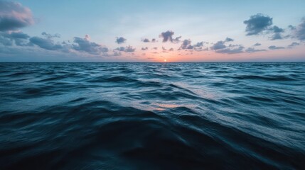 Fototapeta premium Calm ocean waves reflect the soft colors of a distant sunset.