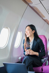  A woman is sitting on an airplane, working and looking at her laptop.