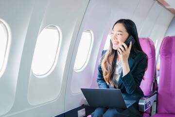  A woman is sitting on an airplane, working and looking at her laptop.