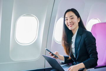  A woman is sitting on an airplane, working and looking at her laptop.