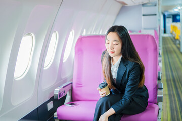  A woman is sitting on an airplane, working and looking at her laptop.