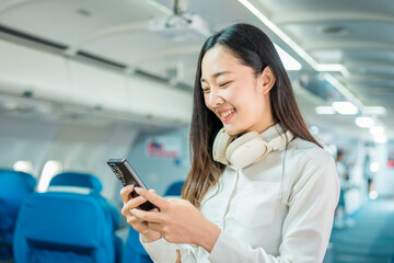  The businesswoman enjoyed her flight by listening to music with wireless headphones and using her smartphone while on the plane.