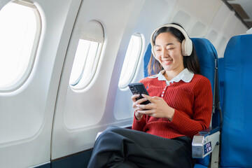  The businesswoman enjoyed her flight by listening to music with wireless headphones and using her smartphone while on the plane.