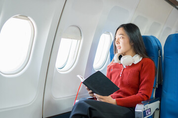 Fototapeta premium A young Asian woman, a passenger on the plane, embarks on a study abroad journey, representing cultural exchange and academic experiences in international education.