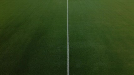Aerial view of an empty sports stadium with green field and blue stands