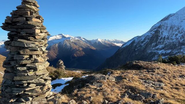mountain landscape with snow ; camera mouving arround a cairn with a view on the Ecrins mountain range