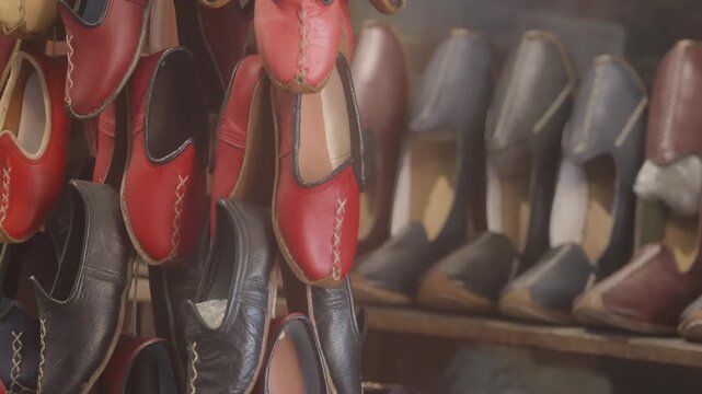 Close-up 10-bit slow motion of traditional handmade leather Yemeni shoes (carik) hanging in a workshop. Highlighting the colorful designs and authentic Turkish craftsmanship. 4K quality.