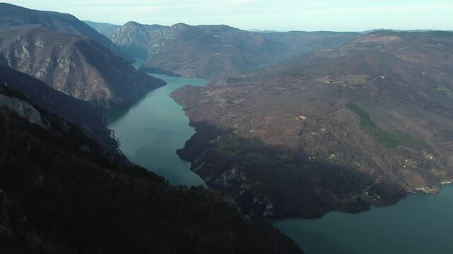 Aerial horizontal view of rocky cliffs and forested slopes in Tara National Park overlooking the Drina River and Perucac Lake during a snowless winter. Scenic natural landscape of western Serbia