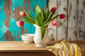 Spring tulip flower bouquet on wooden table over rustic background with kitchen towel