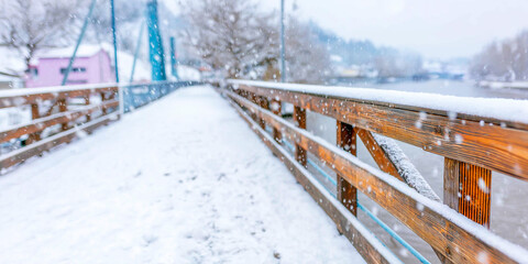 Snow covered wooden railing next to a path along a river during heavy falling snow creates a serene winter scene