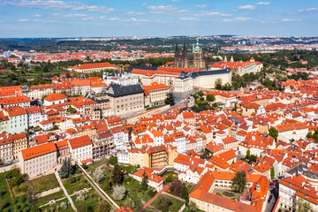 Panoramic view of Prague featuring historic castle and vibrant rooftops on a sunny day in summer. Aerial view of Prague, Czech Republic, showcasing the city's iconic architecture and red-tiled roofs.